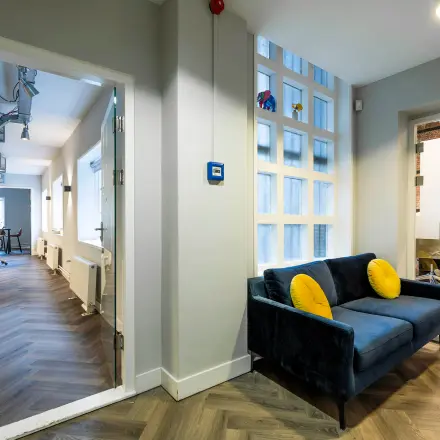 Modern office space at Rapenburgerstraat 173 in Amsterdam Center, featuring a cozy lounge area and workspace setup for rent.