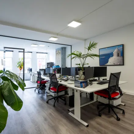 Modern office to rent at Rokin 105 105, Amsterdam Center, featuring a sleek open floorplan with multiple workstations, computers, and greenery.