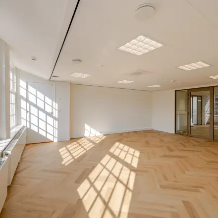 Bright and spacious office space with large windows and wooden flooring at Rokin 117 117, ideal for office space rental in Amsterdam Center.