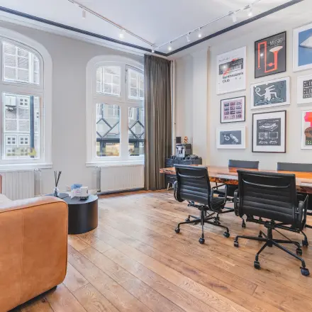 Elegant office space with wooden floors, stylish artwork, and a meeting table with chairs at Warmoesstraat 149 - 151 in Amsterdam Center, available for office space rental.