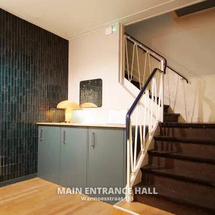 Main entrance hall of Warmoesstraat 155, featuring a staircase and cabinets, ideal for office space rental in Amsterdam Center.