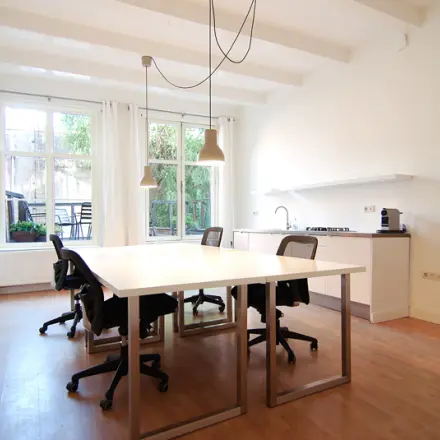 Bright office space at Warmoesstraat 155, Amsterdam Center, featuring modern furnishings and natural light, ideal for workspaces. A perfect office to rent with open layout and seating options.