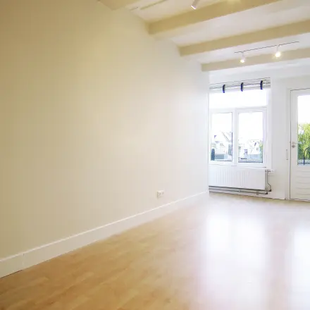 Bright and unfurnished office space for rent at Warmoesstraat 155, Amsterdam Center, featuring large windows and wooden flooring, ideal for office space rental.