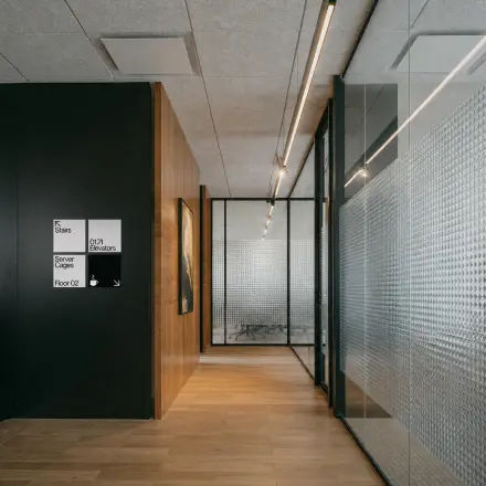Modern office hallway with glass walls and wooden flooring at Weteringschans 26, Amsterdam Center, ideal for office space rental.
