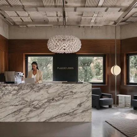 Modern reception area at Weteringschans 126, Amsterdam Center, with a marble desk and someone working at a laptop. Ideal office space rental opportunity.