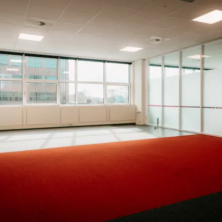 Spacious and sunlit office to rent at Overschiestraat 182, Amsterdam De Schinkel featuring large windows and carpeted floors, ideal for office space rental.