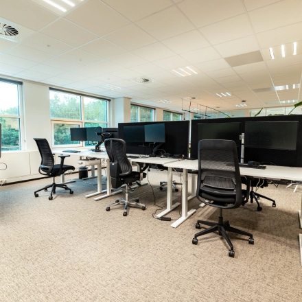Modern office space for rent in Overschiestraat 186, Amsterdam De Schinkel, featuring multiple workstations with chairs and monitors under a bright and spacious interior.