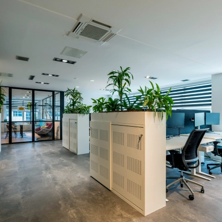 Modern office space at Overschiestraat 186 in Amsterdam De Schinkel featuring workstations with chairs and screens, divided by planters.