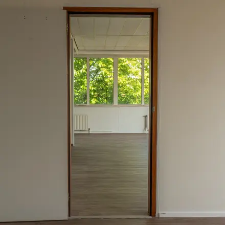 Unfurnished office space with wooden flooring and large windows at James Wattstraat 71, ideal for rent office space in Amsterdam East.