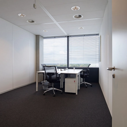 Office space with desks and chairs overlooking a cityscape at Piet Heinkade 55, ideal for those seeking office space rental in Amsterdam East.