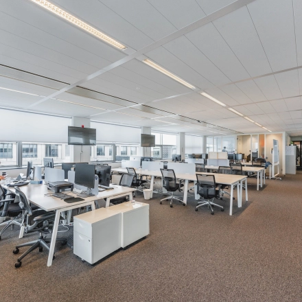 Bright, modern office space at Piet Heinkade 95B in Amsterdam East, featuring rows of desks and large windows, ideal for office space rental.