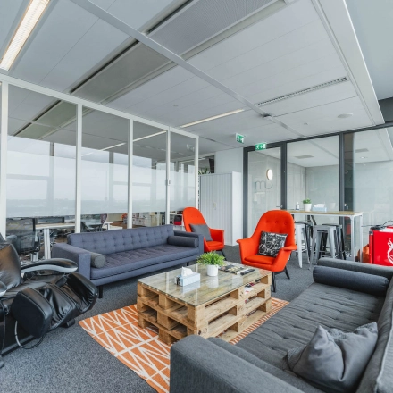 Bright office space featuring modern furnishings with couches and chairs, ideal for office space rental in Amsterdam East at Piet Heinkade 95B.