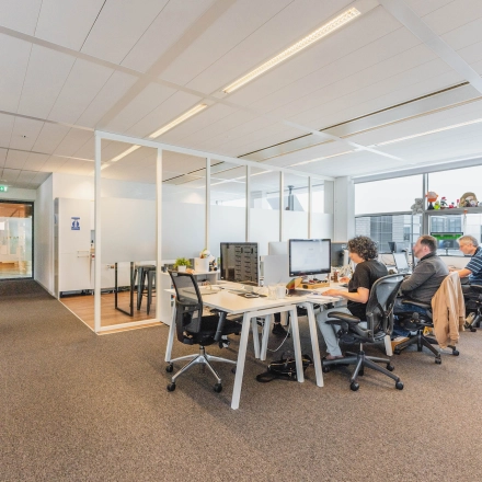 Office to rent at Piet Heinkade 95B in Amsterdam East, featuring modern workspaces with professionals engaged in tasks at their desks.