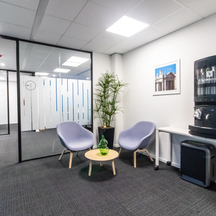 Modern office space in Amsterdam East with lounge chairs, a coffee machine, and a small table, perfect for short breaks. Ideal for those seeking office space rental.