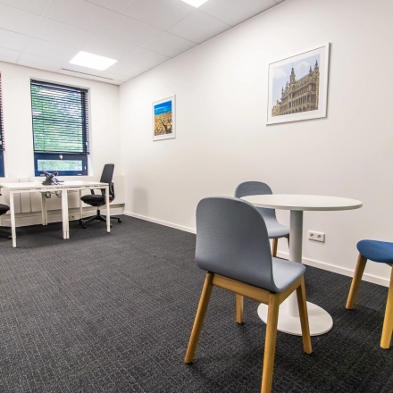Bright office space rental at Rhijnspoorplein 10-38, Amsterdam East, with modern furnishings including desks and chairs, set against large windows for natural light.