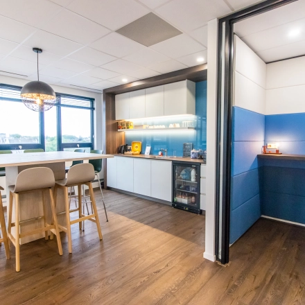 Bright office space in Amsterdam East featuring a furnished pantry area with a long table and chairs, ideal for casual meetings or breaks.