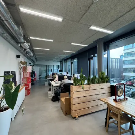 Spacious office space in Amsterdam Houthavens, featuring modern design with wooden planters and large windows for ample natural light. Ideal office to rent for vibrant workspaces.