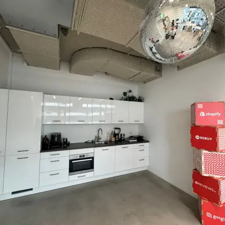 Modern kitchenette in an office space with sleek white cabinets and a disco ball ceiling feature, perfect for office space rental in Amsterdam Houthavens.