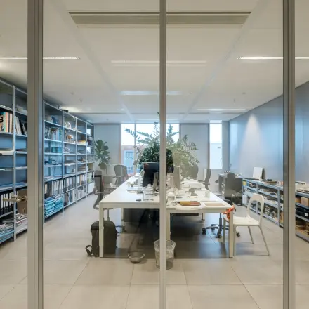 Modern office space at Pedro de Medinalaan 7, Amsterdam IJburg, featuring a long table, shelving with organized materials, and a bright, inviting atmosphere. Ideal for office space rental.
