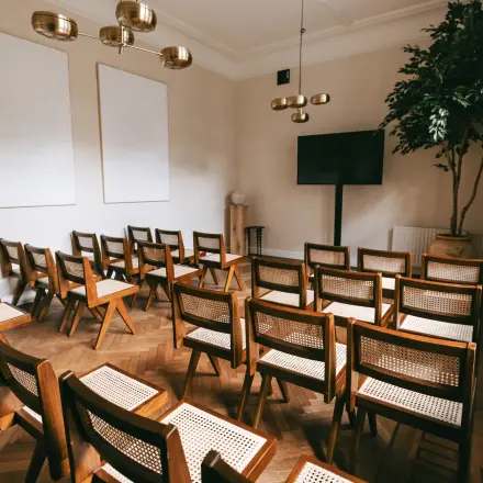 Light-filled conference room at Emmalaan 7-9 in Amsterdam Old South, featuring neatly arranged wooden chairs and a large screen. Ideal for office space rental.