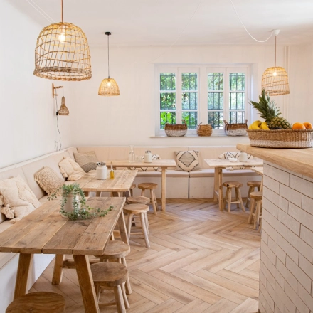 A cozy office to rent in Amsterdam Old South with wooden tables, cushioned benches, and natural light through large windows, perfect for work or meetings. Ideal for office space rental.
