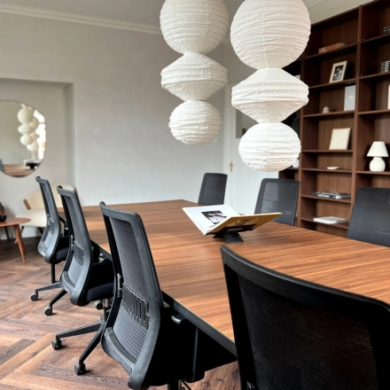 Office space with a long wooden table, black chairs, pendant lights, and a bookshelf, available for rent at Emmalaan 7-9, Amsterdam Old South.
