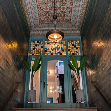 Entrance area at Emmalaan 7-9, Amsterdam Old South, showcasing decorative tiles and stained glass, perfect for those looking to rent office space.