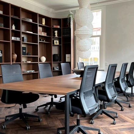 Furnished office space at Emmalaan 7-9, Amsterdam Old South, featuring a meeting table with chairs and wooden shelving in the background, ideal for office space rental.
