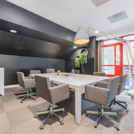 Modern office space rental in Amsterdam Old South featuring a conference room with a long table, ergonomic chairs, and bright natural lighting at Olympisch Stadion 24-28.