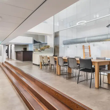 Spacious modern office with long meeting table and seating, featuring sleek design and ample lighting at Olympisch Stadion 24-28, perfect for office space rental in Amsterdam Old South.