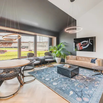 Stylish office lounge at Olympisch Stadion 24-28, Amsterdam Old South, featuring modern furniture, a rug, and large windows. Ideal office space rental.