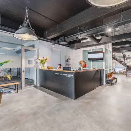 Reception area of an office space available for rent at Olympisch Stadion 24-28, Amsterdam Old South, featuring a welcoming desk, potted plants, and modern furnishings.