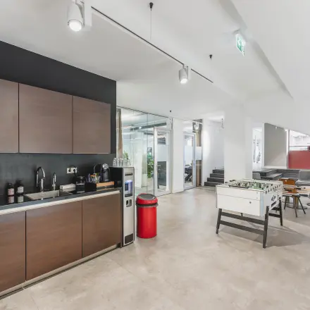 Modern office space rental in Amsterdam Old South featuring a sleek kitchenette and spacious recreational area with a foosball table at Olympisch Stadion 24-28.