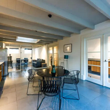 Modern office space with sleek furnishings in Amsterdam Old South, featuring a round table, stylish chairs, and an elegant kitchen area, ideal for office space rental.