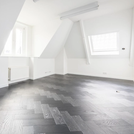 Bright, empty interior office space with sloped ceilings and wooden flooring at Sophialaan 21, ideal for office space rental in Amsterdam Old South.