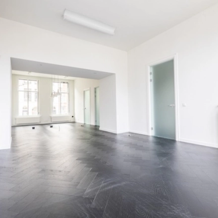 Spacious, unfurnished office space with dark wooden floors and large windows at Sophialaan 21, Amsterdam Old South. Ideal for office space rental.