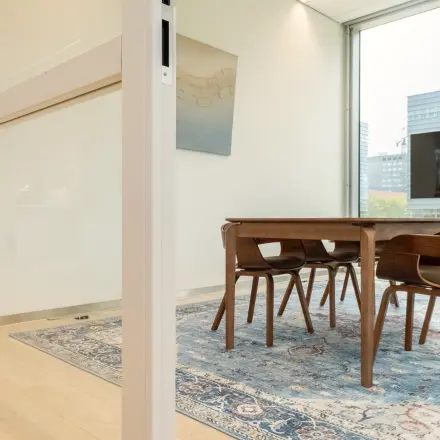 Bright office space in Amsterdam Riekerpolder at David Ricardostraat 1, featuring a conference room with a wooden table, chairs, and large windows.