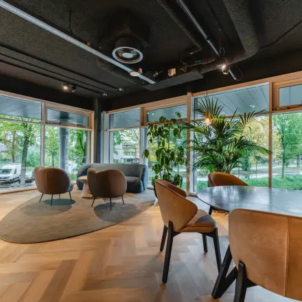 Modern office space with large windows, stylish seating, and wooden flooring at John M. Keynesplein 4-10, ideal for rent office space in Amsterdam Riekerpolder.