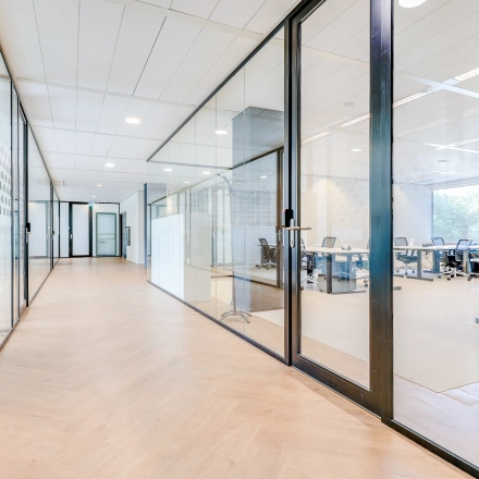 Bright hallway leading to furnished office spaces with glass partitions, ideal for office space rental in Amsterdam Riekerpolder.