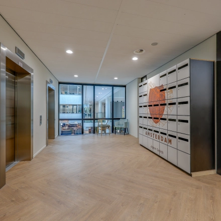 Office entrance in Amsterdam Riekerpolder with modern design, featuring an elevator and Amsterdam-themed decor, available for office space rental.