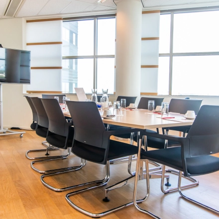 A bright conference room at Radarweg 29, Amsterdam Sloterdijk, available for office space rental with a large table, chairs, and a screen.