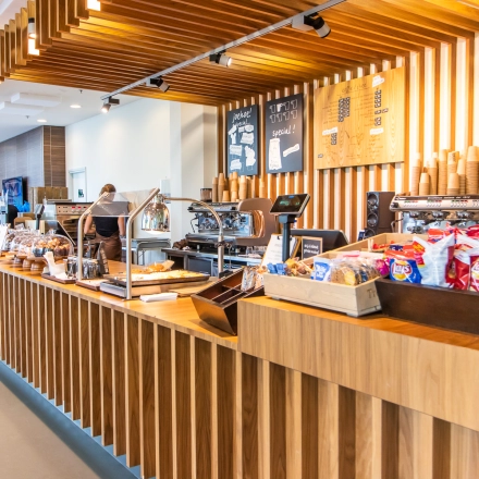 A welcoming pantry area at office space rental on Radarweg 29, Amsterdam Sloterdijk, featuring light wood decor and a variety of snacks for employees. A person is preparing coffee at a machine.