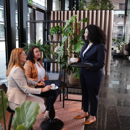 Office space at Teleportboulevard 110 in Amsterdam Sloterdijk, featuring a lively work environment with people seated at tables, engaged in conversation, surrounded by plants and modern decor.