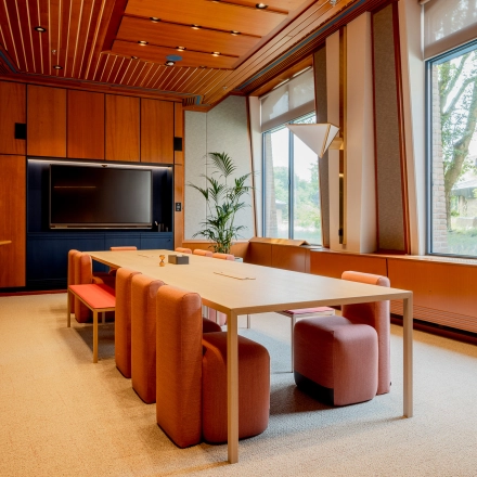 A furnished office space at Bijlmerplein 888, Amsterdam South East, featuring a wooden conference table and chairs with a large window view, ideal for rent office space needs.