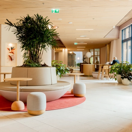 Modern office space in Amsterdam South East with stylish seating area and greenery, ideal for office space rental. Features natural light and vibrant design at Bijlmerplein 888.