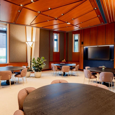 Spacious office interior at Bijlmerplein 888 in Amsterdam South East with round tables and chairs, ideal for office space rental. Features warm lighting and large windows.