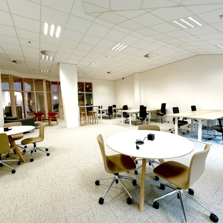 Spacious, well-lit office space with modern furnishings at Bijlmerplein 888, ideal for rent in Amsterdam South East. Features multiple desks and chairs, suitable for various business activities.