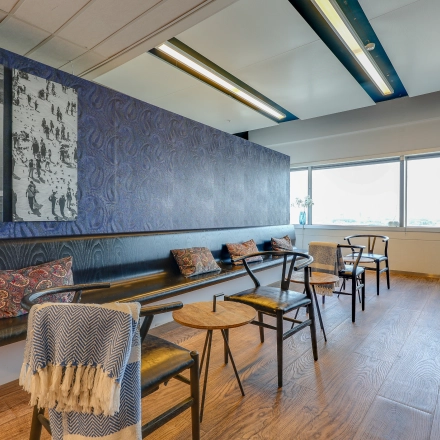 Bright office space in Amsterdam South East with seating and decorative wall art, available for office space rental.