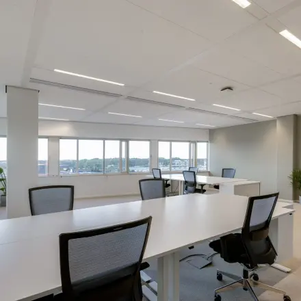 Spacious office to rent at Herikerbergweg 288, Amsterdam South East, featuring modern desks and chairs with large windows allowing ample natural light.