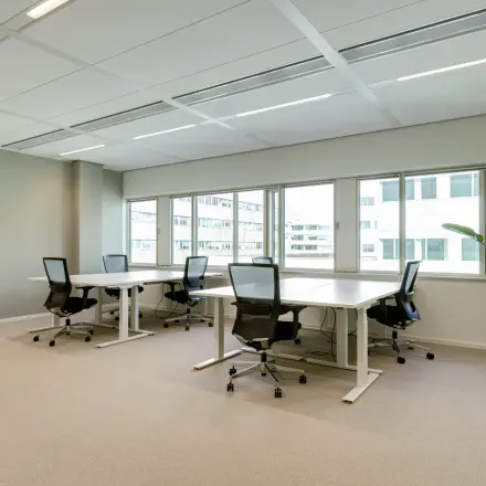 Bright office space at Herikerbergweg 288, Amsterdam South East, featuring large windows and furnished with desks and chairs, available for rent.